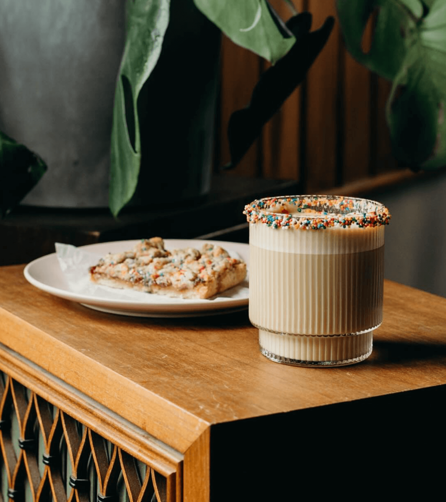 a frothy iced coffee with sprinkles and a pastry on a table